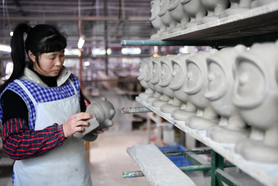 1月19日，在泉州德化县陶瓷旅游观光工厂的制坯成型车间，工人打磨“冰墩墩”。